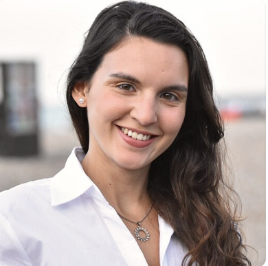 Belén Cangiano smiles at the camera, a young brunette woman wearing a white shirt